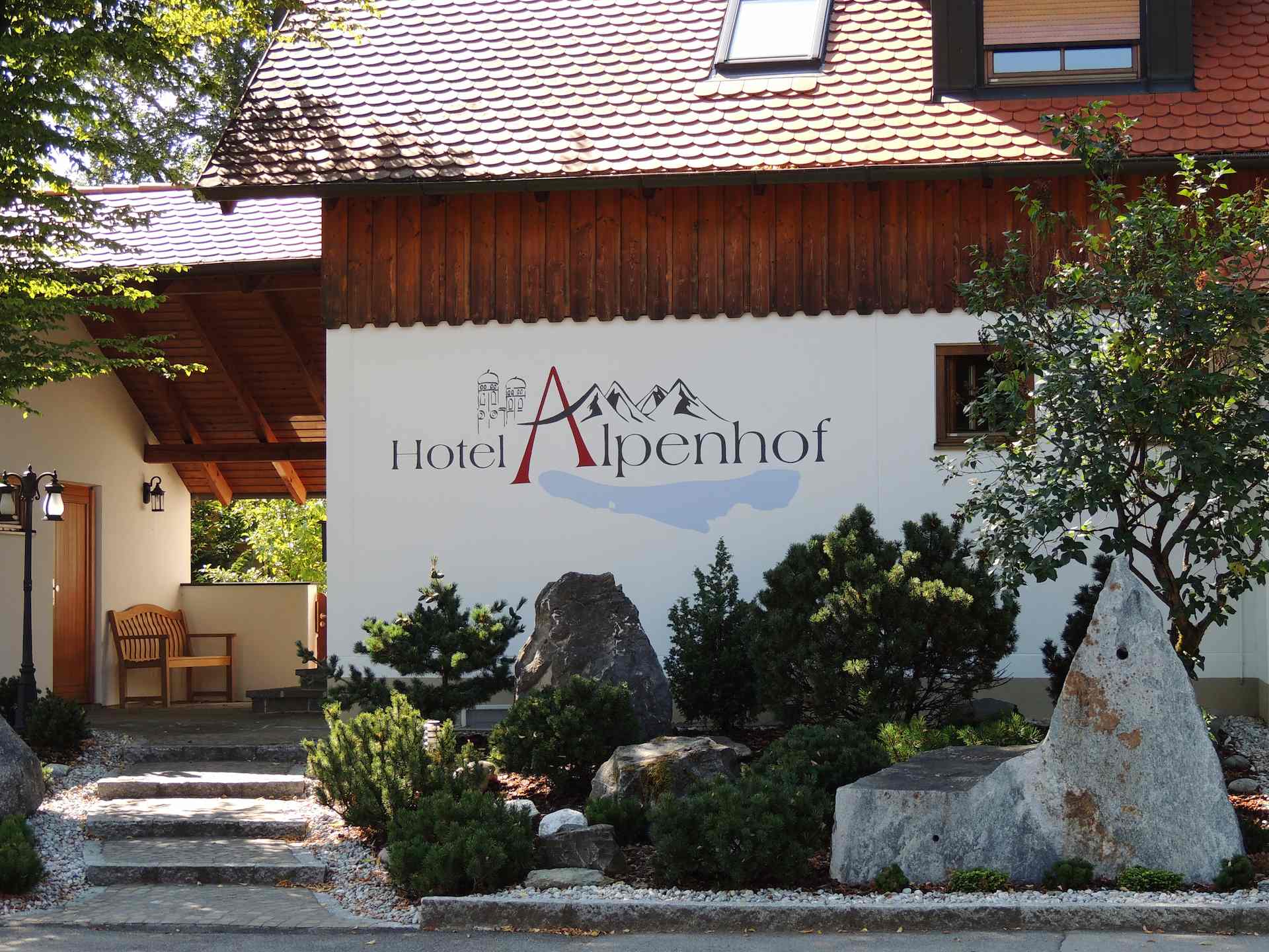 Hotel Alpenhof Gauting – Außenansicht mit Steingarten im Frühling